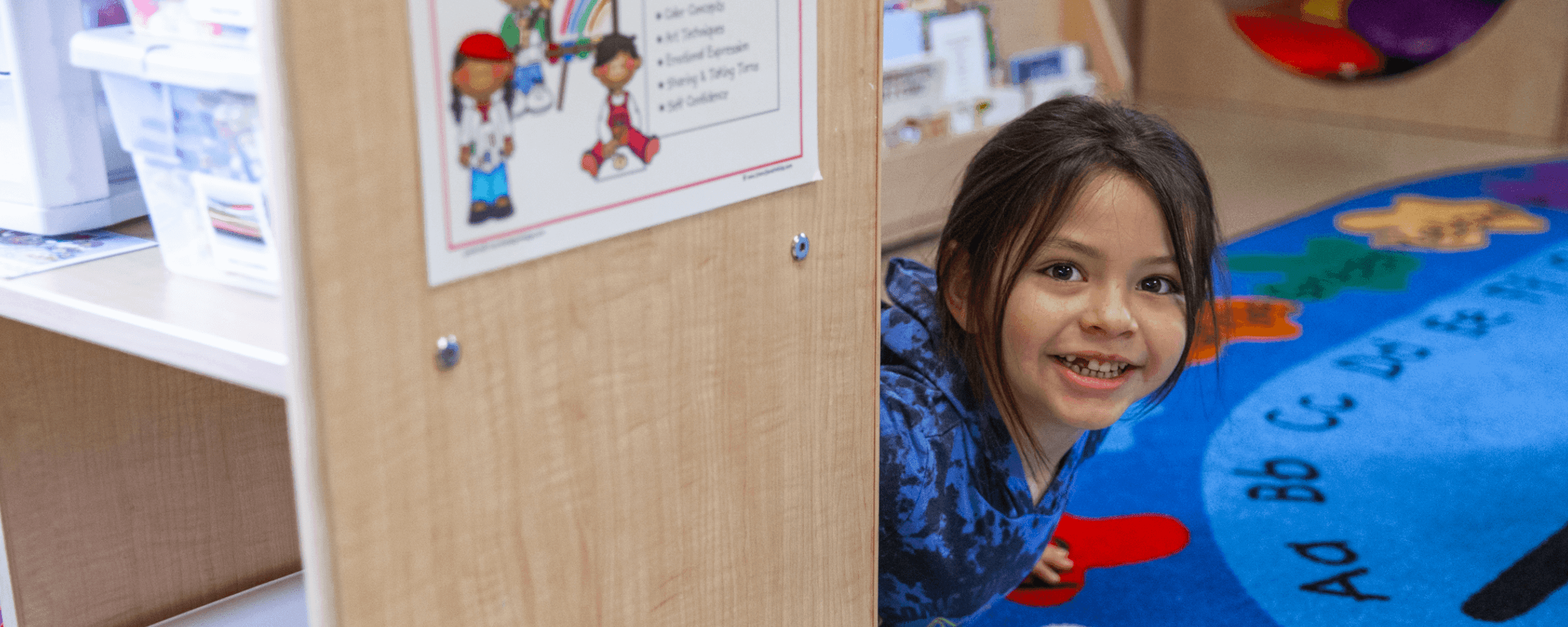 Preschool boy peeking his head out from behind a book shelf