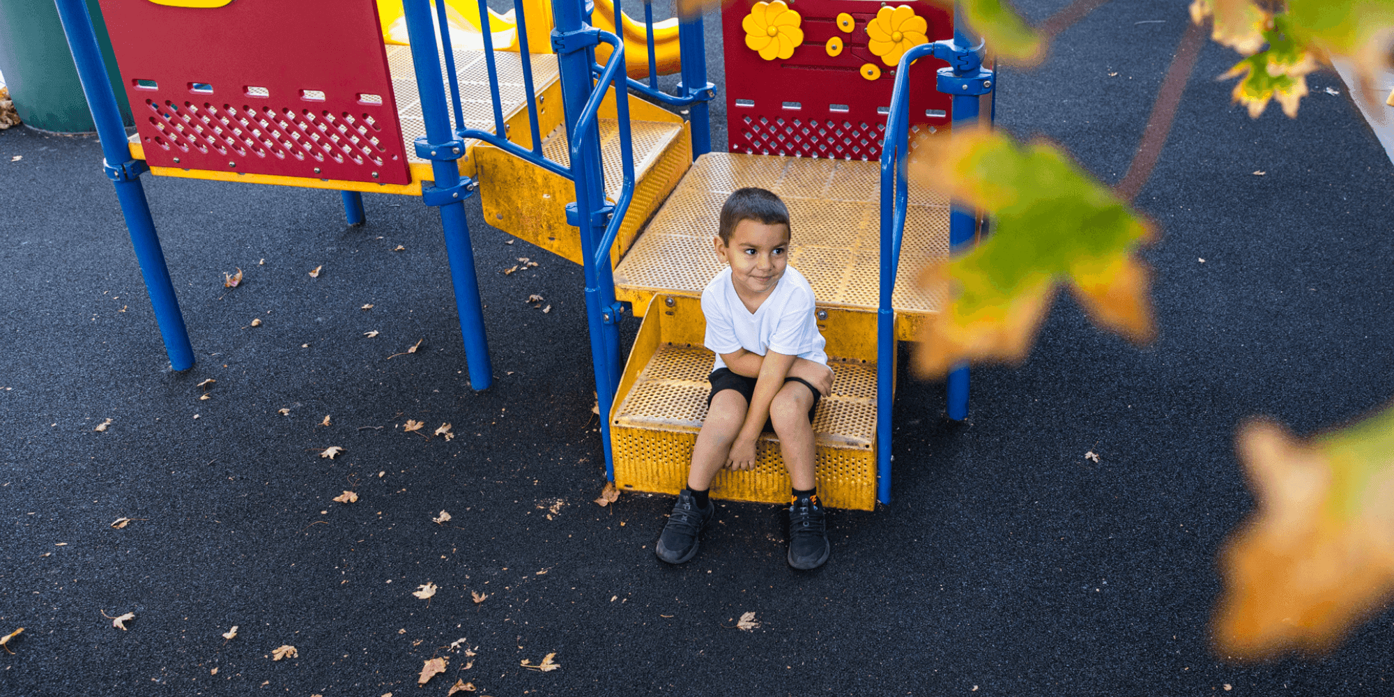 Preschool boy sitting on the steps of a playground